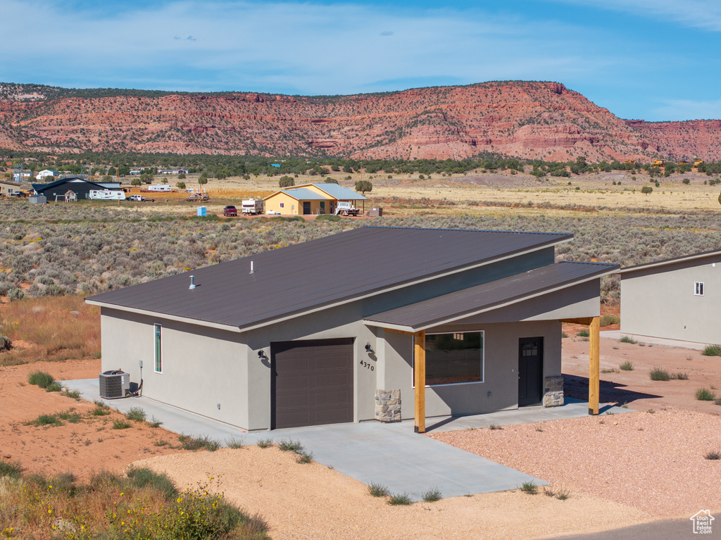 View of front of house with a garage, central air condition unit, and a mountain view