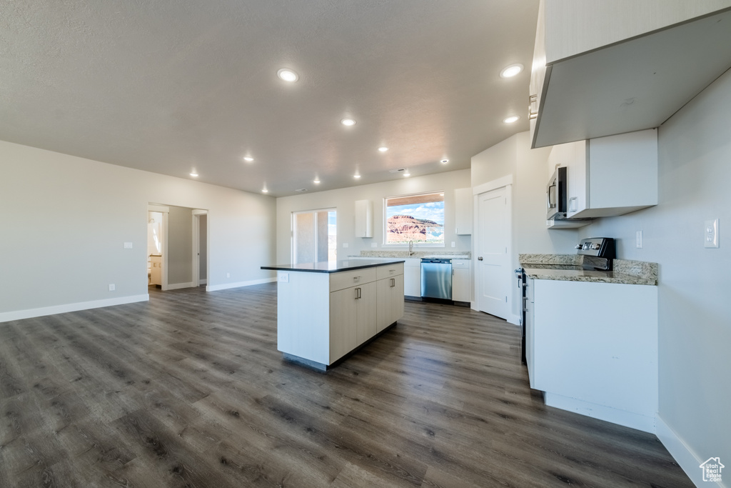 Kitchen with white cabinets, appliances with stainless steel finishes, dark wood-type flooring, and a kitchen island