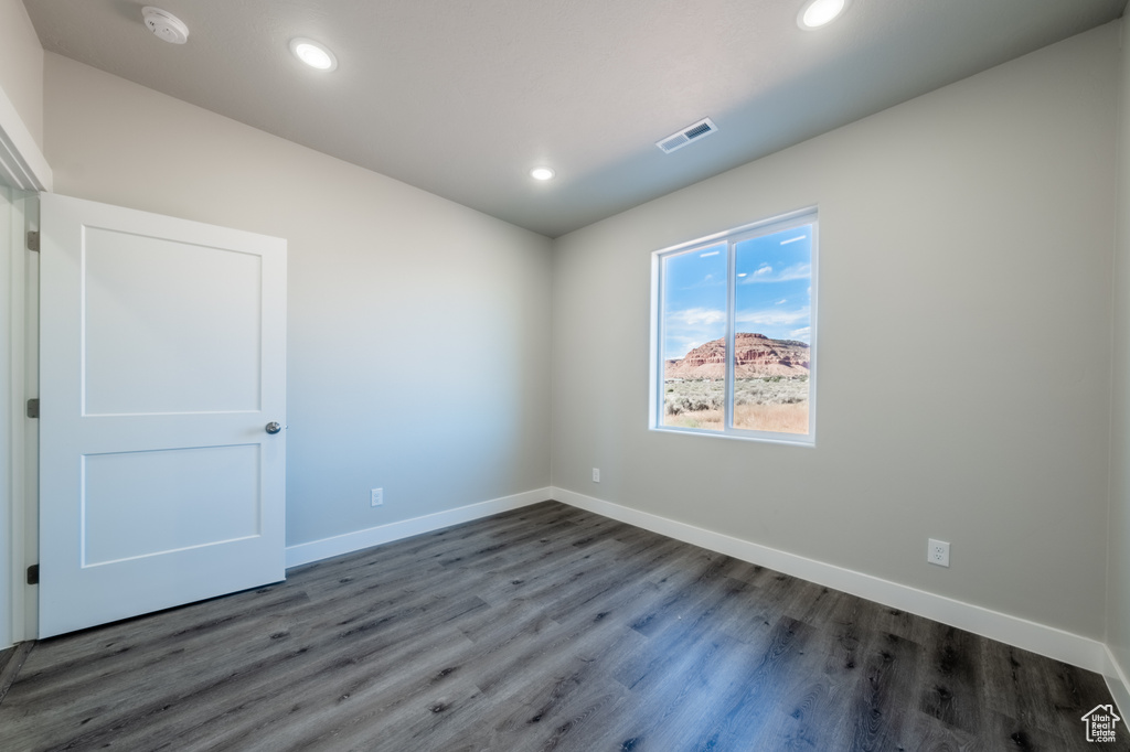 Empty room featuring dark hardwood / wood-style flooring