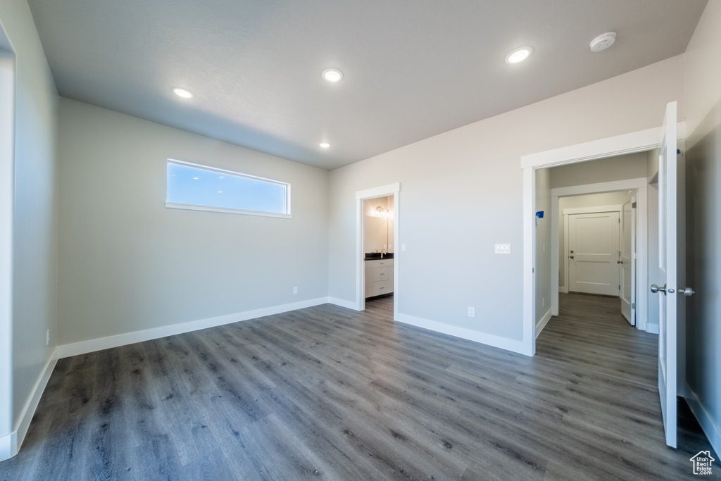 Unfurnished bedroom with ensuite bath and dark wood-type flooring