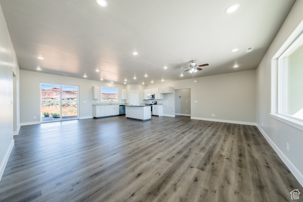 Unfurnished living room featuring ceiling fan, dark wood-type flooring, and sink