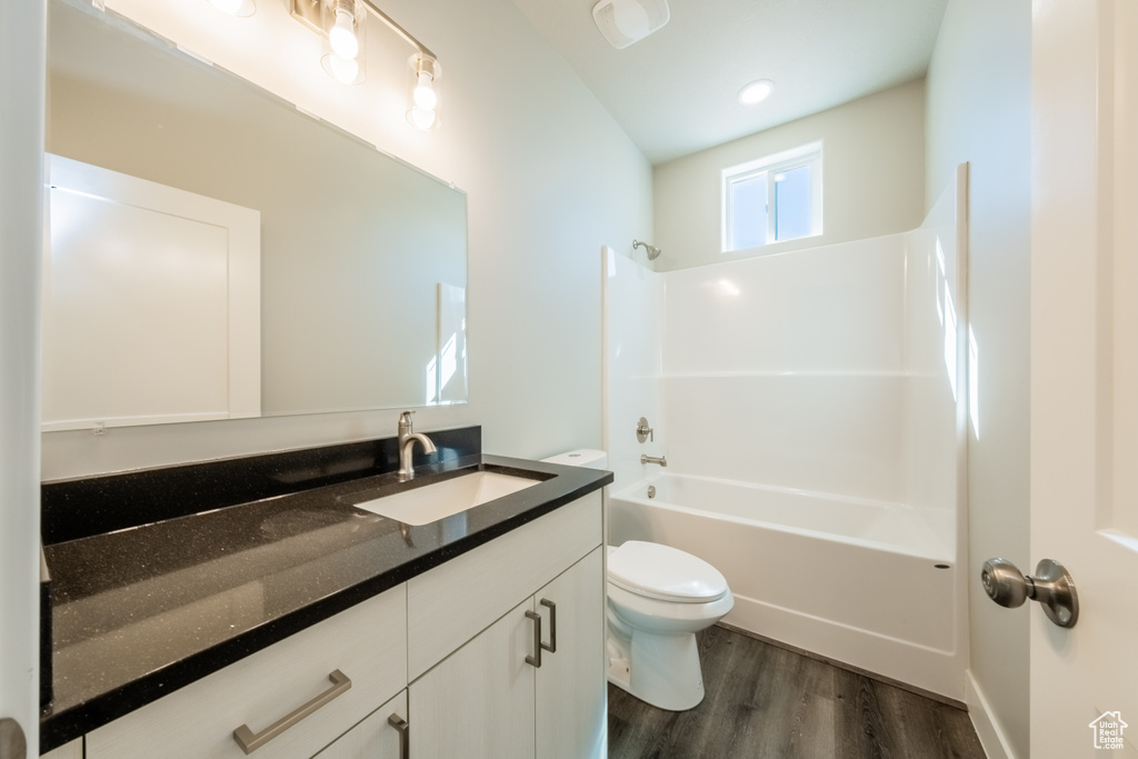 Full bathroom with vanity, toilet, shower / bath combination, and hardwood / wood-style flooring