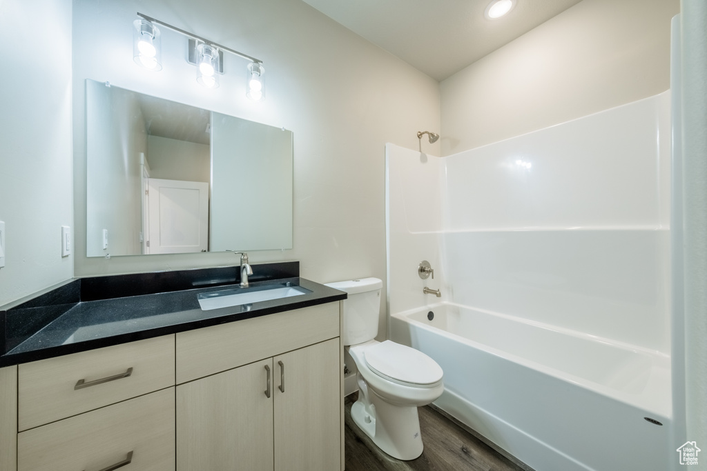 Full bathroom with wood-type flooring, shower / washtub combination, vanity, and toilet