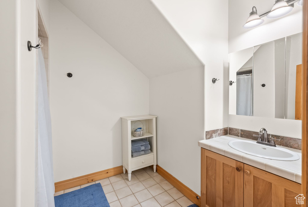 Bathroom with tile floors, lofted ceiling, and vanity