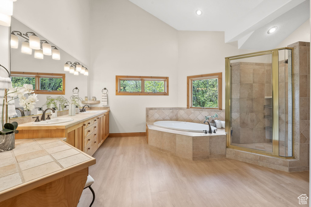 Bathroom featuring a high ceiling, hardwood / wood-style flooring, independent shower and bath, and double sink vanity