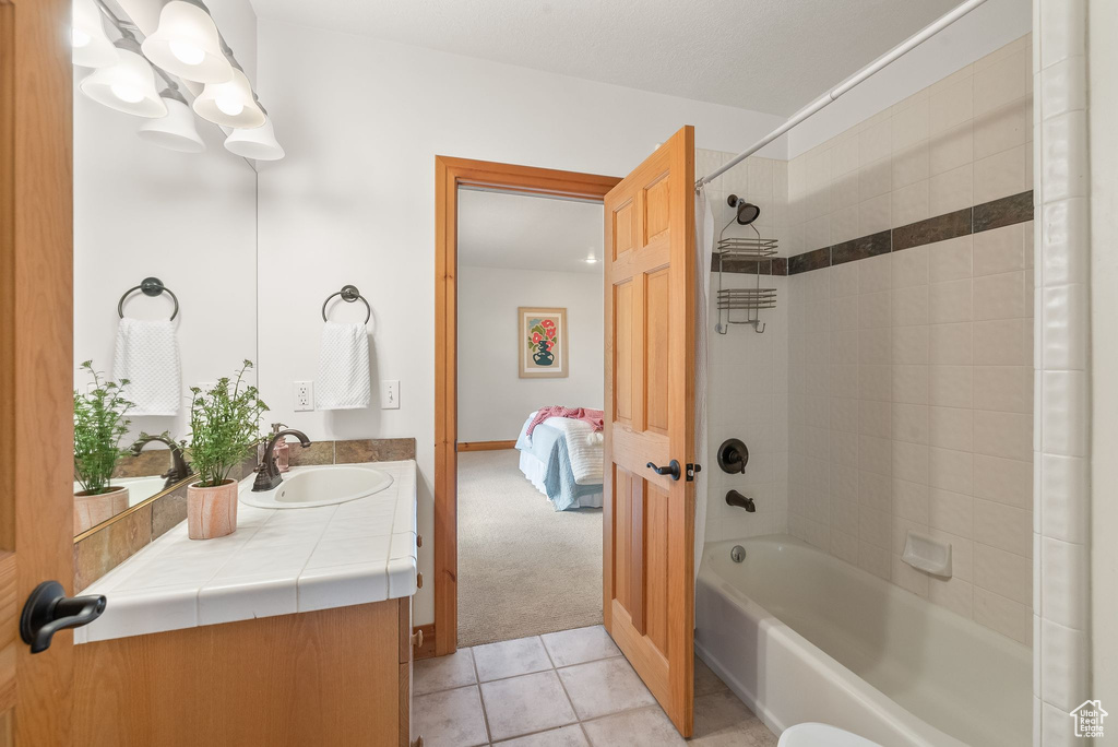 Bathroom with tiled shower / bath combo, tile floors, and vanity