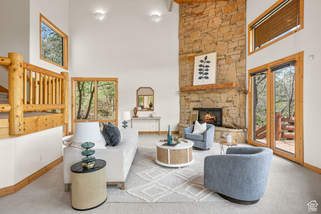 Carpeted living room featuring a healthy amount of sunlight, french doors, a fireplace, and a towering ceiling