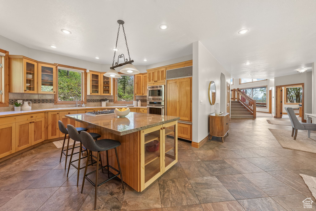 Kitchen featuring tasteful backsplash, plenty of natural light, a kitchen island, and dark tile flooring