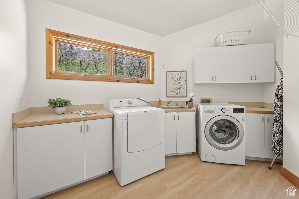 Laundry room featuring light hardwood / wood-style flooring, washer hookup, and cabinets