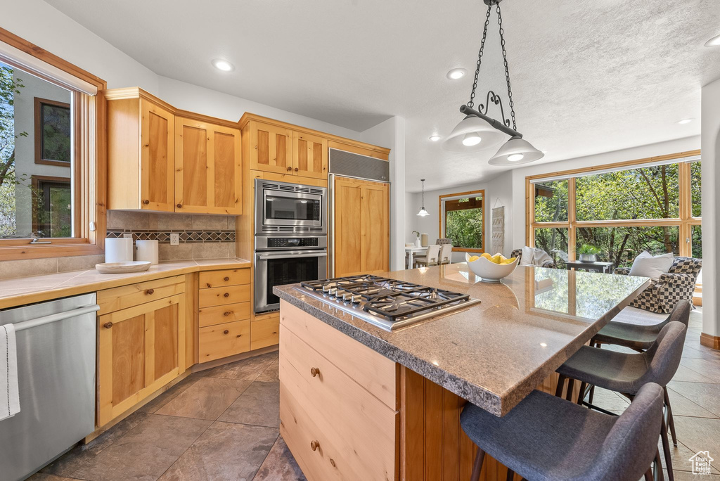 Kitchen featuring a kitchen island, dark tile floors, tasteful backsplash, and built in appliances