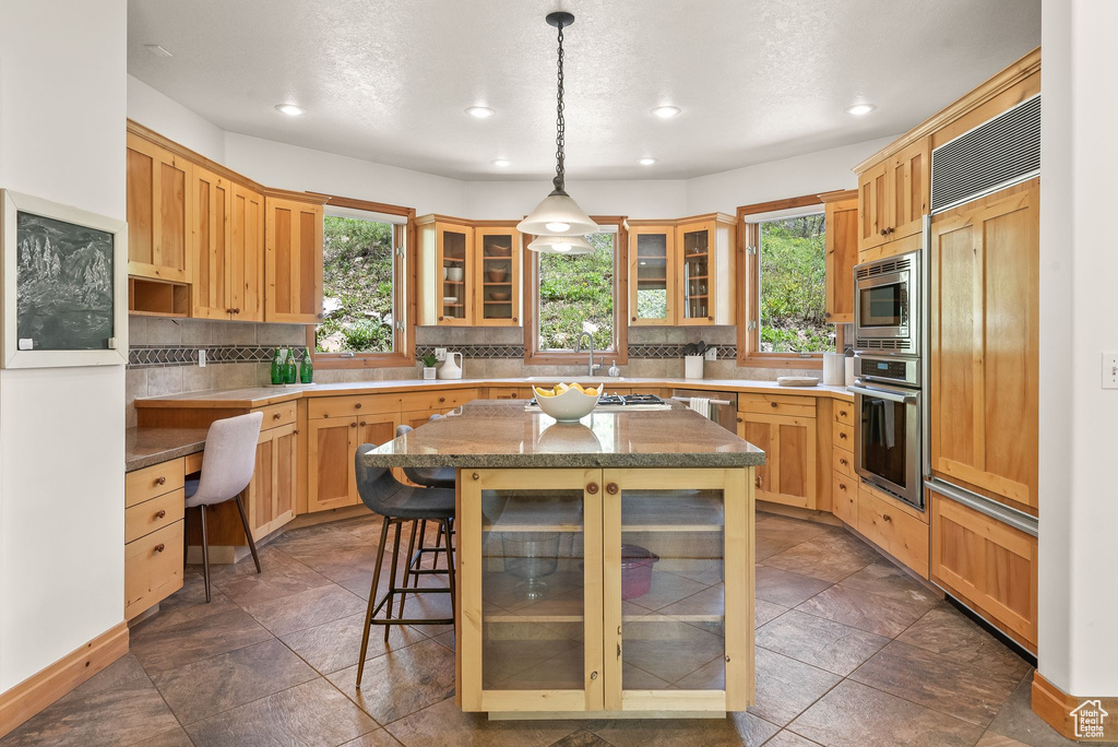 Kitchen featuring a center island, a wealth of natural light, built in appliances, and backsplash