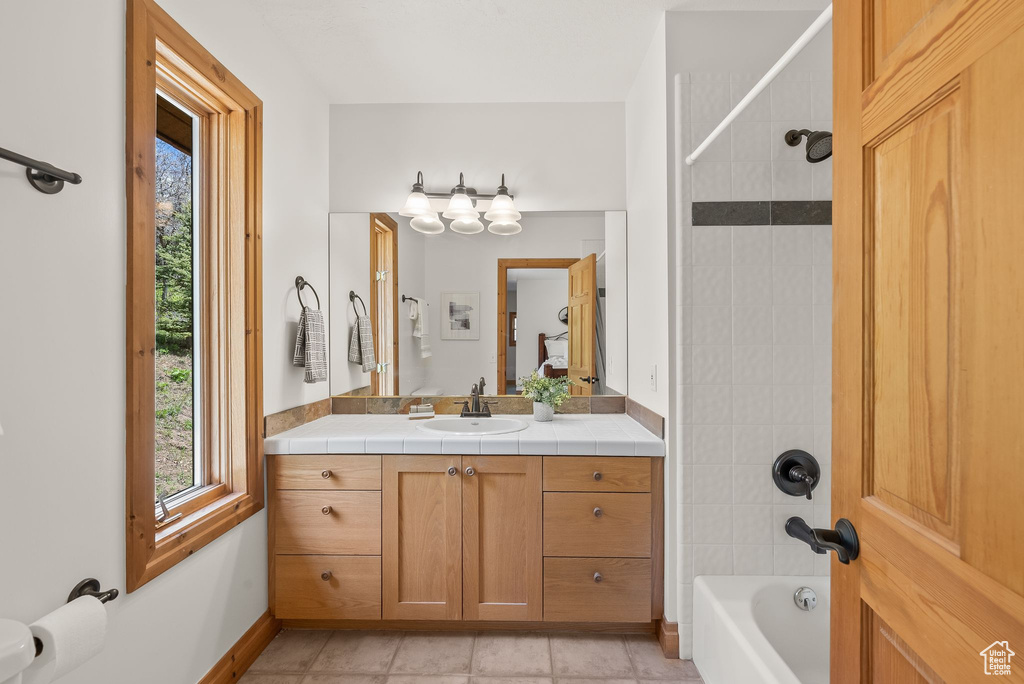 Full bathroom featuring tile flooring, toilet, vanity, and tiled shower / bath