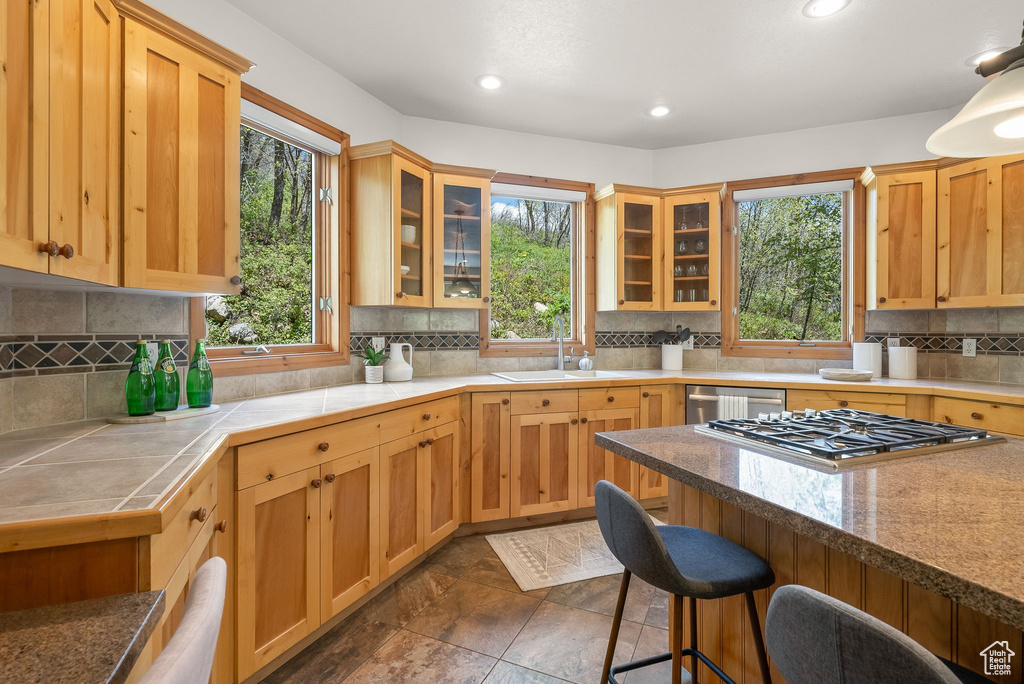 Kitchen with sink, plenty of natural light, dark tile floors, and tasteful backsplash