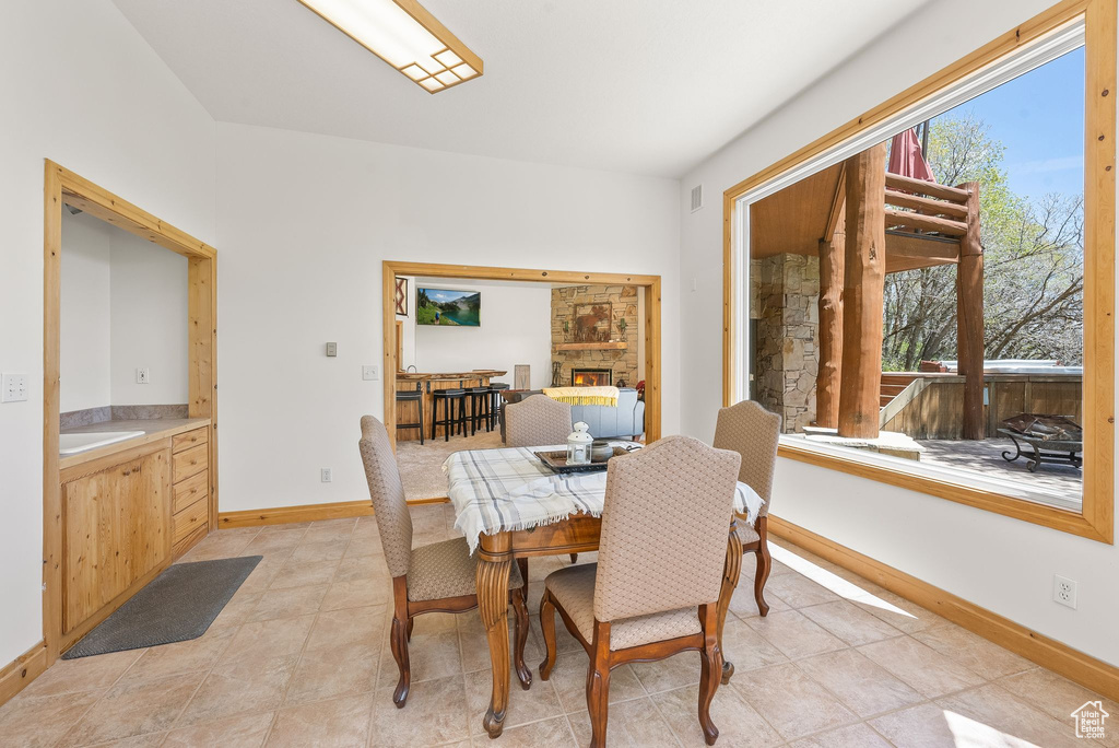 Dining space with light tile flooring and a large fireplace