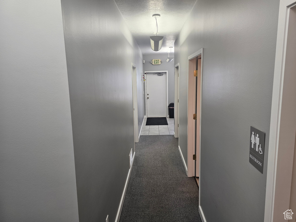 Hallway with dark tile flooring and a textured ceiling