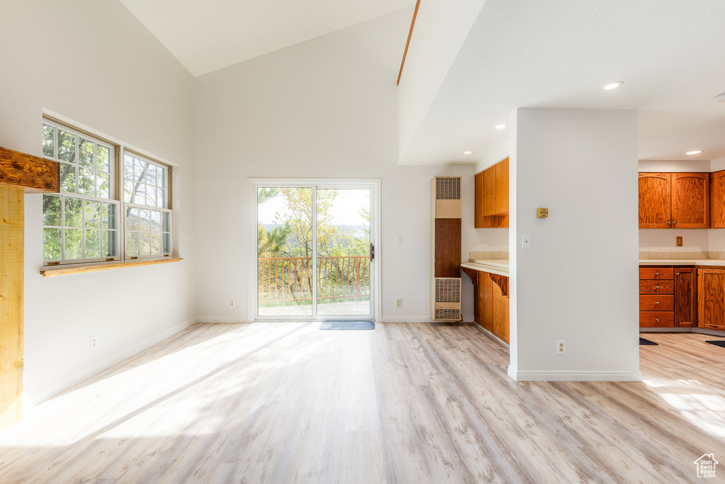 Unfurnished living room featuring light hardwood / wood-style floors and high vaulted ceiling