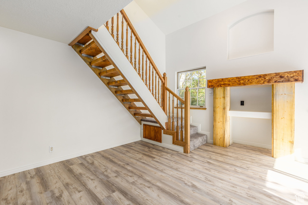 Staircase with a towering ceiling and hardwood / wood-style floors