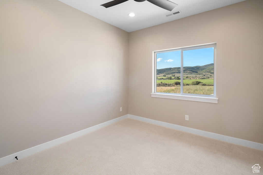 Empty room featuring ceiling fan and carpet flooring