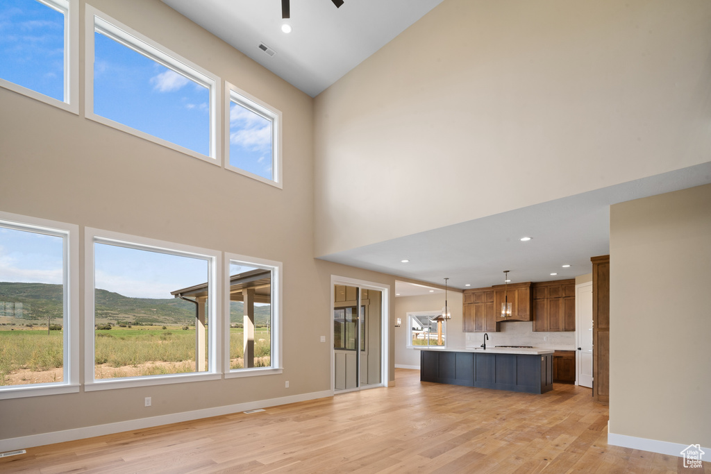 Unfurnished living room with high vaulted ceiling, plenty of natural light, and light hardwood / wood-style flooring