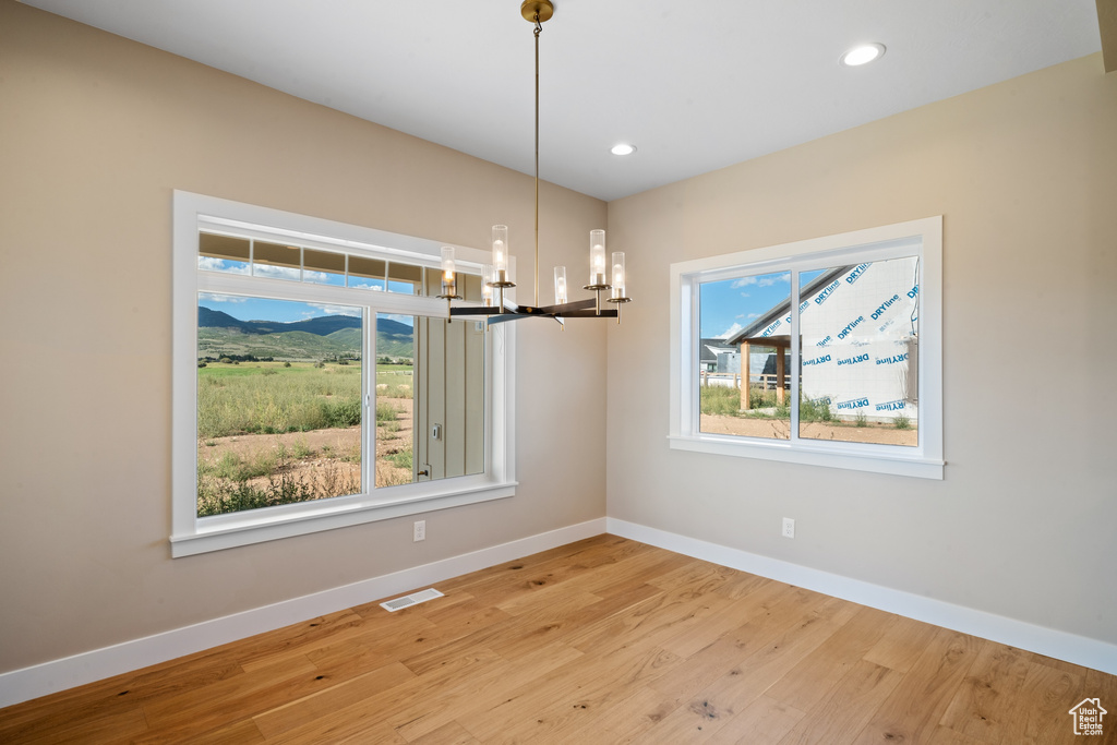 Unfurnished dining area featuring light hardwood / wood-style floors and an inviting chandelier