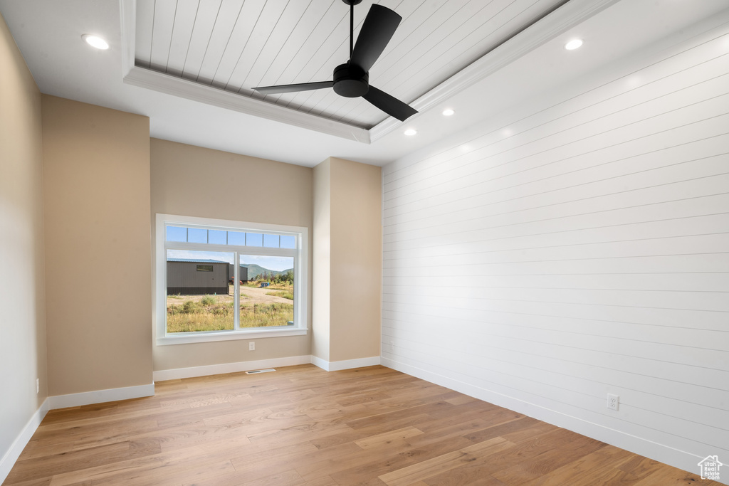 Unfurnished room featuring ceiling fan, light hardwood / wood-style floors, and a tray ceiling