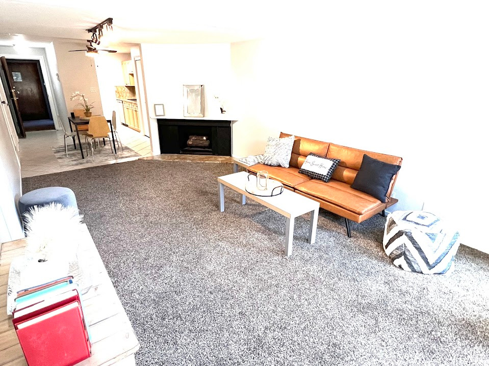 Carpeted living room with a multi sided fireplace and ceiling fan