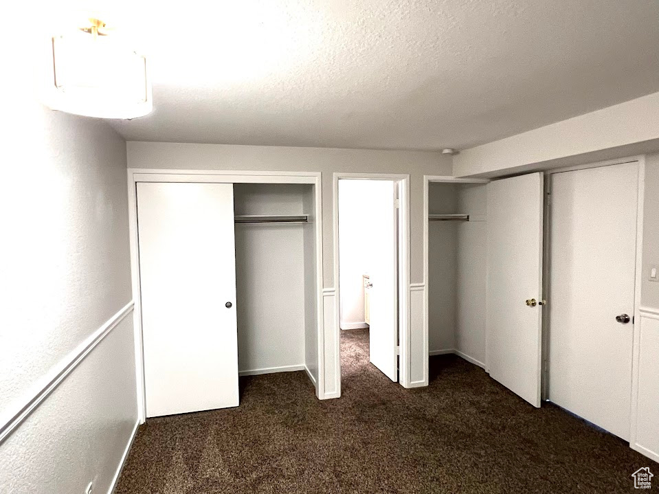 Unfurnished bedroom with two closets and dark colored carpet