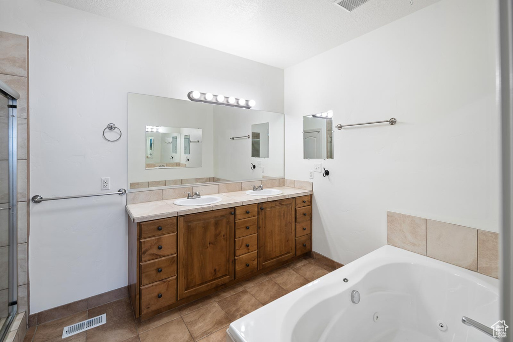 Bathroom with double vanity, walk in shower, a textured ceiling, and tile floors