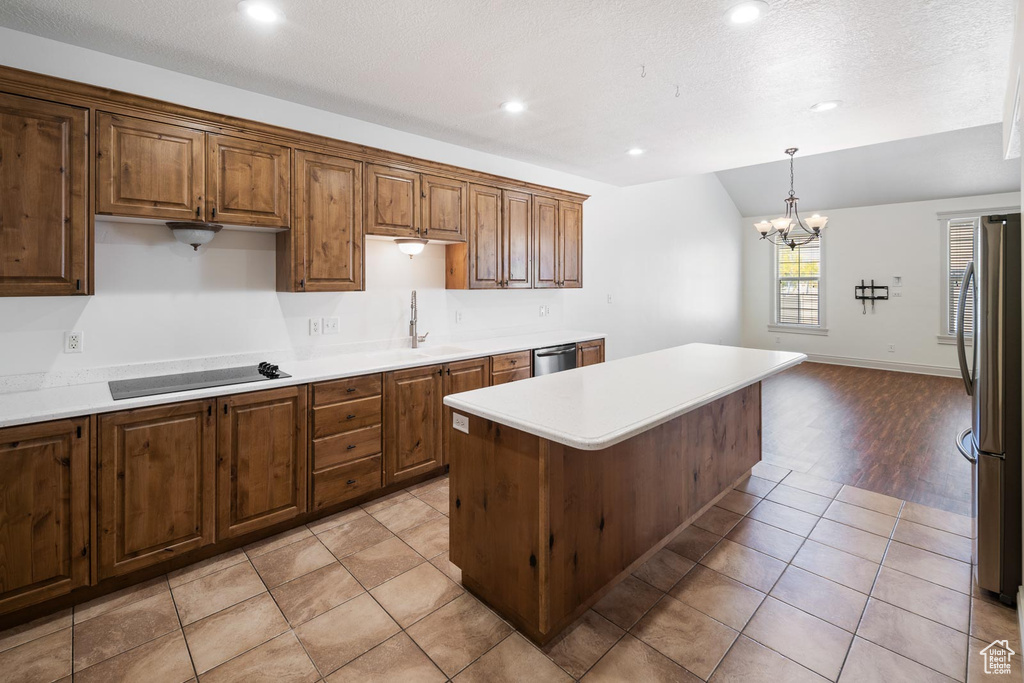 Kitchen with a center island, stainless steel appliances, pendant lighting, a chandelier, and light tile flooring