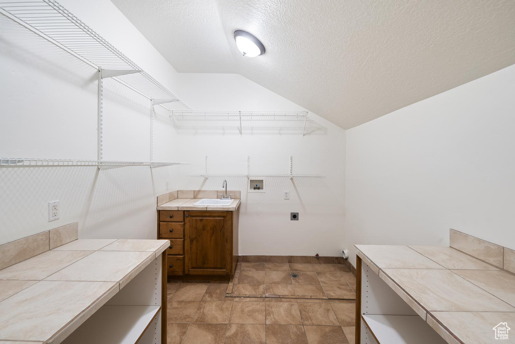 Walk in closet featuring sink, lofted ceiling, and light tile flooring