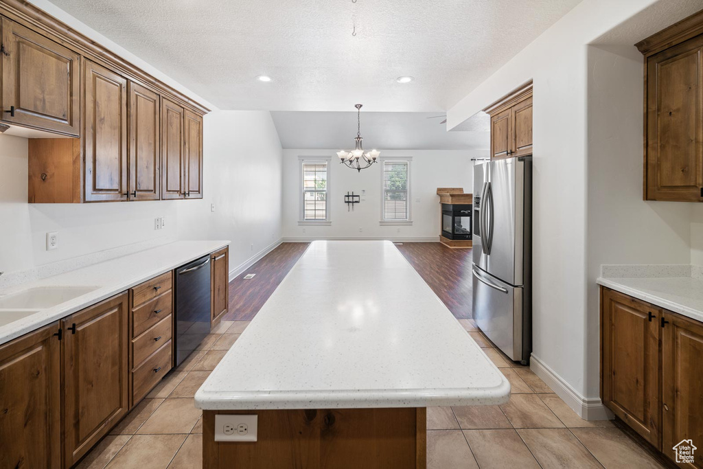 Kitchen featuring dishwasher, a center island, light tile flooring, and stainless steel refrigerator with ice dispenser