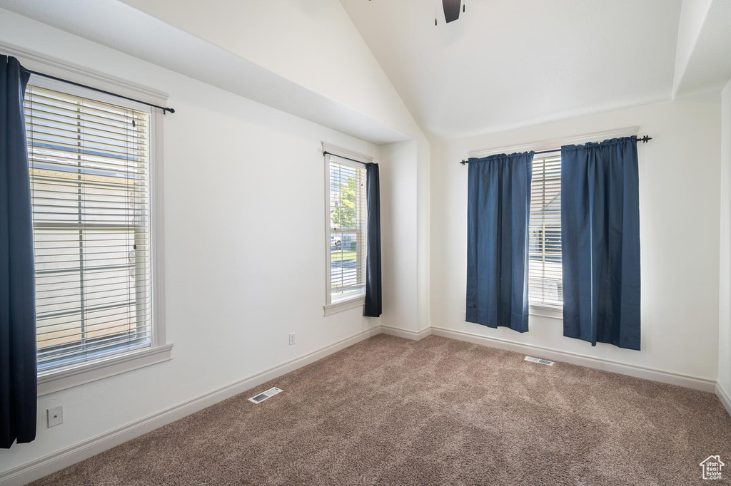 Empty room with vaulted ceiling and carpet