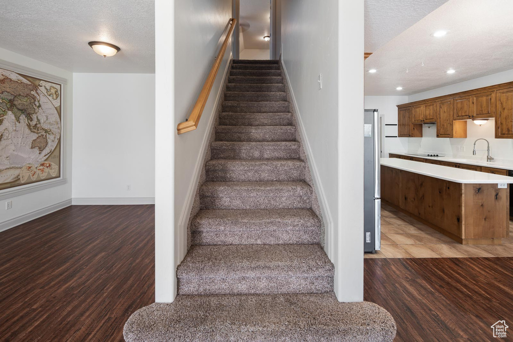 Stairs with sink, a textured ceiling, and hardwood / wood-style floors