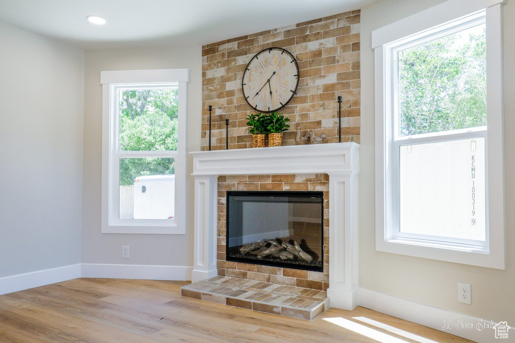 Unfurnished living room with wood-type flooring and a brick fireplace