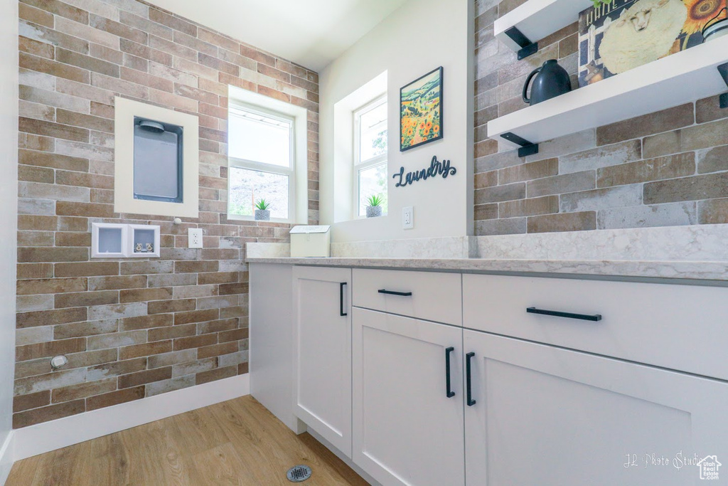 Bathroom featuring hardwood / wood-style flooring, brick wall, and vanity