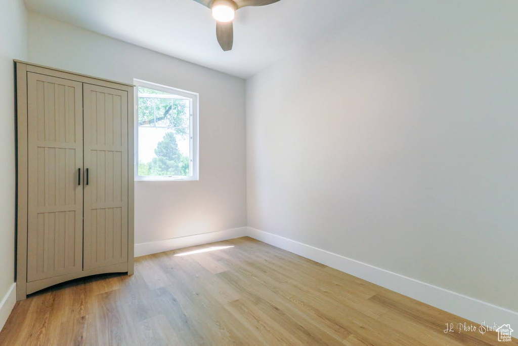 Empty room with ceiling fan and light hardwood / wood-style flooring