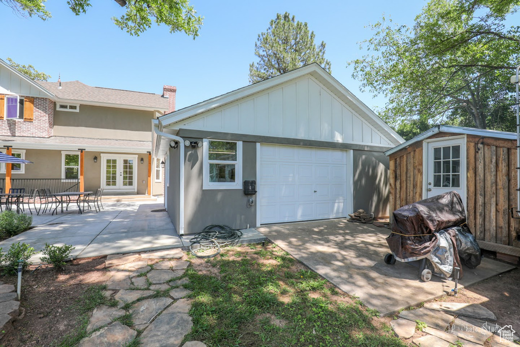 Back of house featuring a patio, a garage, an outdoor structure, and french doors