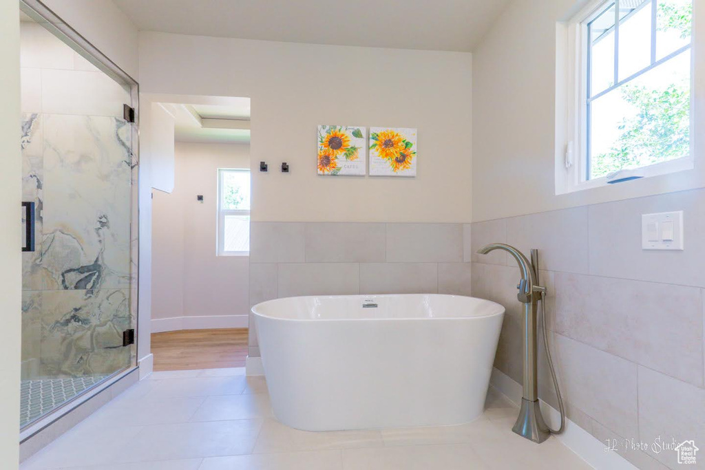 Bathroom with tile flooring, shower with separate bathtub, and tile walls