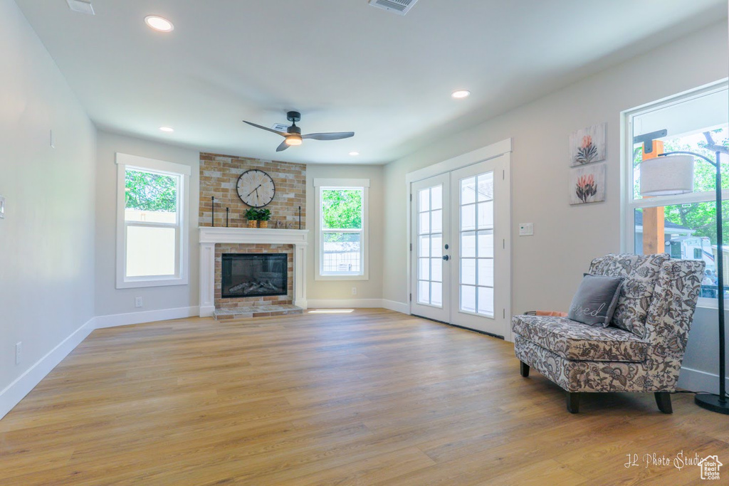 Unfurnished room with french doors, plenty of natural light, light hardwood / wood-style floors, and a fireplace