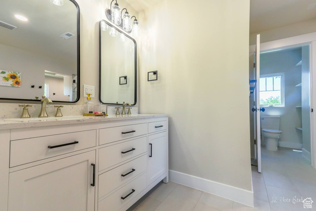 Bathroom featuring double sink vanity, toilet, and tile floors