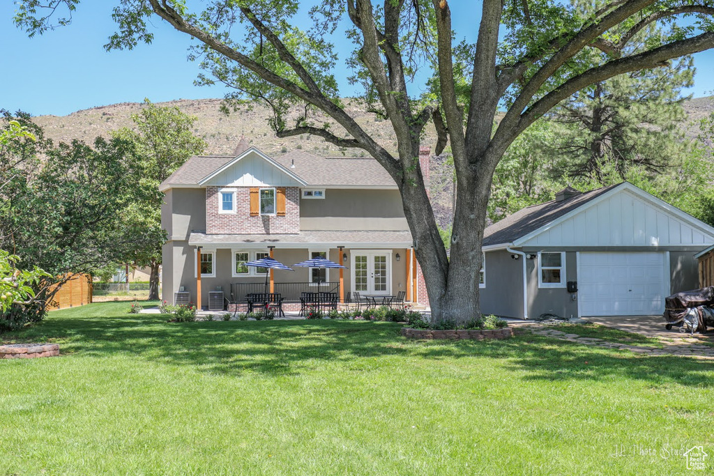 Back of property featuring a garage, a lawn, and an outdoor structure