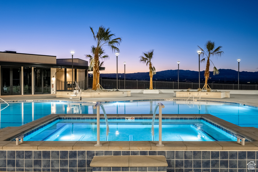 Pool at dusk featuring a community hot tub and a mountain view