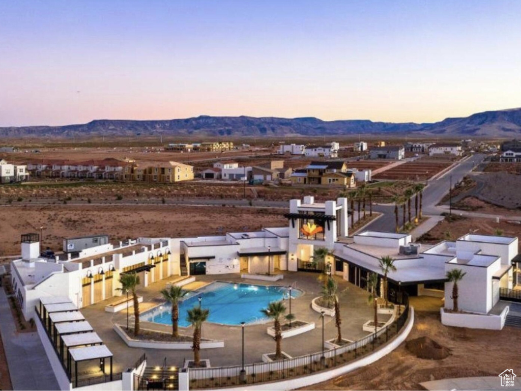 Pool at dusk featuring a mountain view and a patio