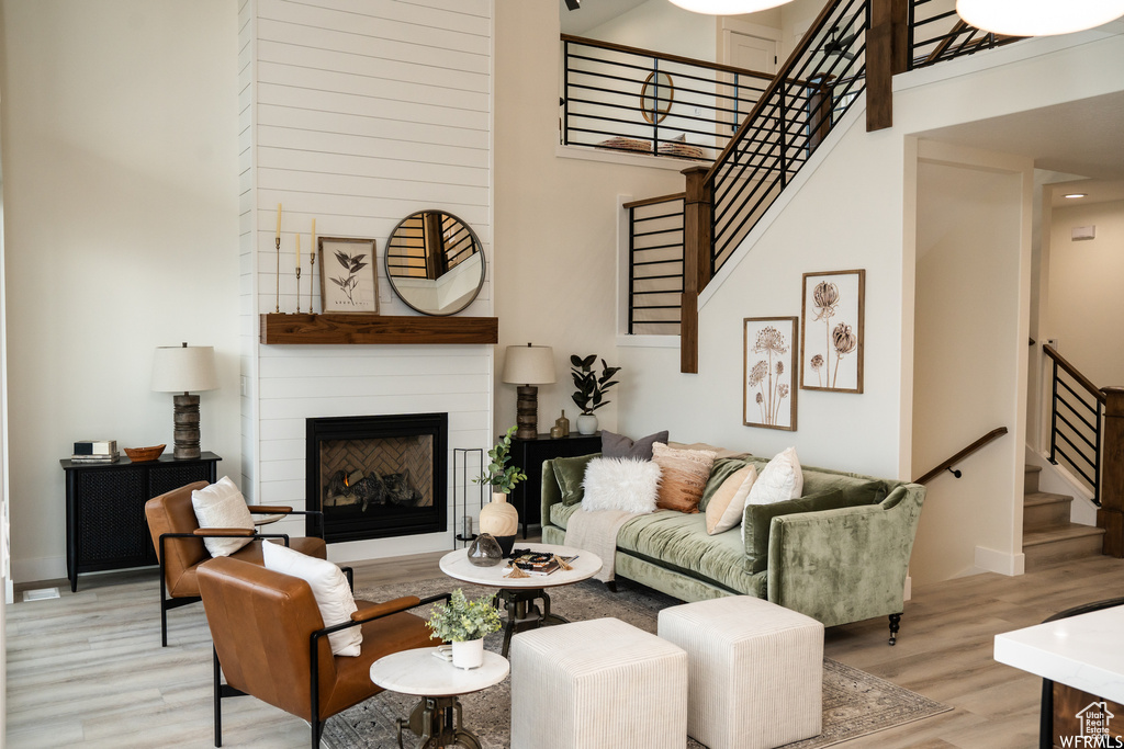 Living room featuring a towering ceiling, light hardwood / wood-style flooring, and a fireplace