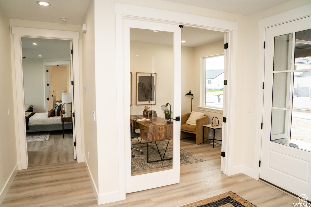 Hallway with a wealth of natural light and light hardwood / wood-style flooring