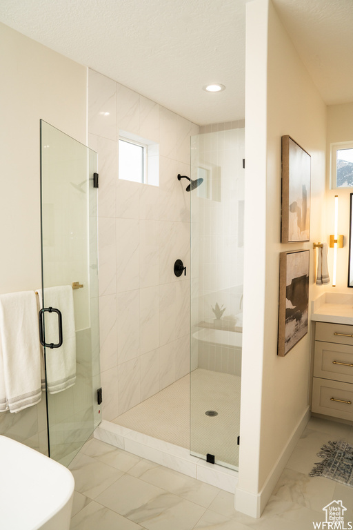 Bathroom featuring walk in shower, tile flooring, vanity, and a textured ceiling