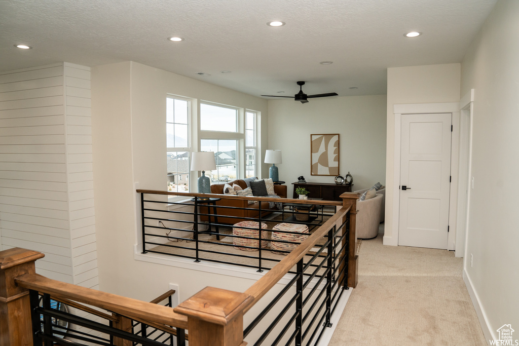 Staircase with light carpet, ceiling fan, and a textured ceiling