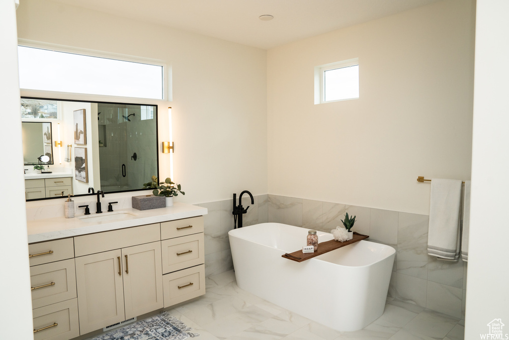 Bathroom featuring tile walls, tile floors, separate shower and tub, and vanity