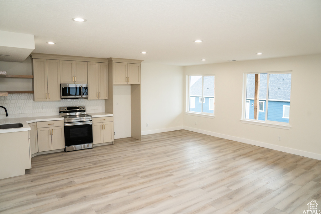 Kitchen featuring sink, tasteful backsplash, light hardwood / wood-style flooring, and stainless steel appliances