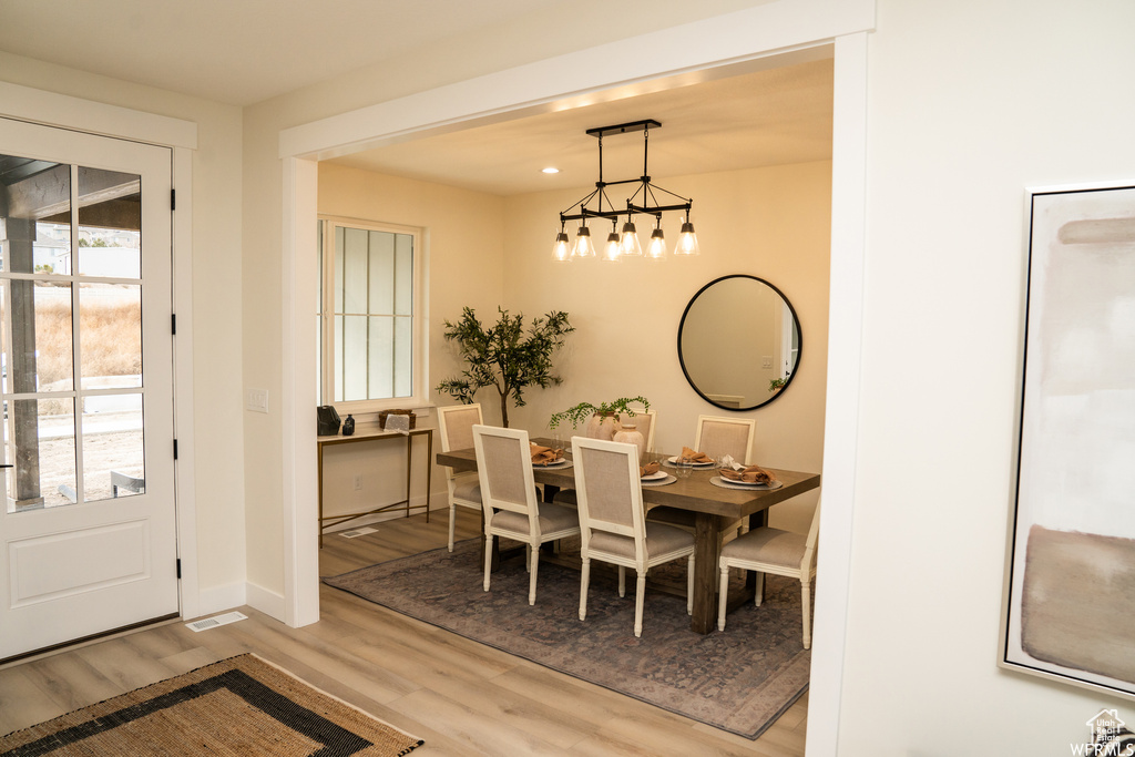 Dining space with an inviting chandelier, hardwood / wood-style floors, and a wealth of natural light